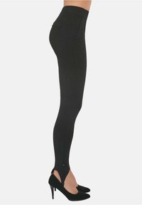 Czarne legginsy z wysokim stanem, gładką teksturą, tapered fit i unikalnym rozcięciem na dole, zestawione z czarnymi szpilkami.