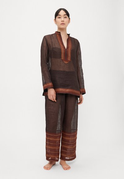 Pruuni lina tuunika V-kaelusega, kaunistatud oranži ja punase triibulise detailiga, sobitatud laiade jalgadega pükstega, mis on samuti triibulise mustriga.