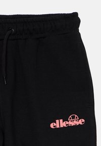 Melni treniņbikses ar elastīgu jostu un auklu. Uz kreisās puses ir rozā "ellesse" logo. Izgatavotas no mīksta džerzeja materiāla.