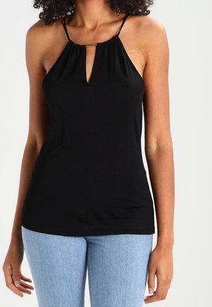 Czarna bezrękawnikowa bluzka z dekoltem w kształcie łezki, regulowanymi ramiączkami i miękkiego materiału. Połączona z jasnoniebieskimi dżinsami.
