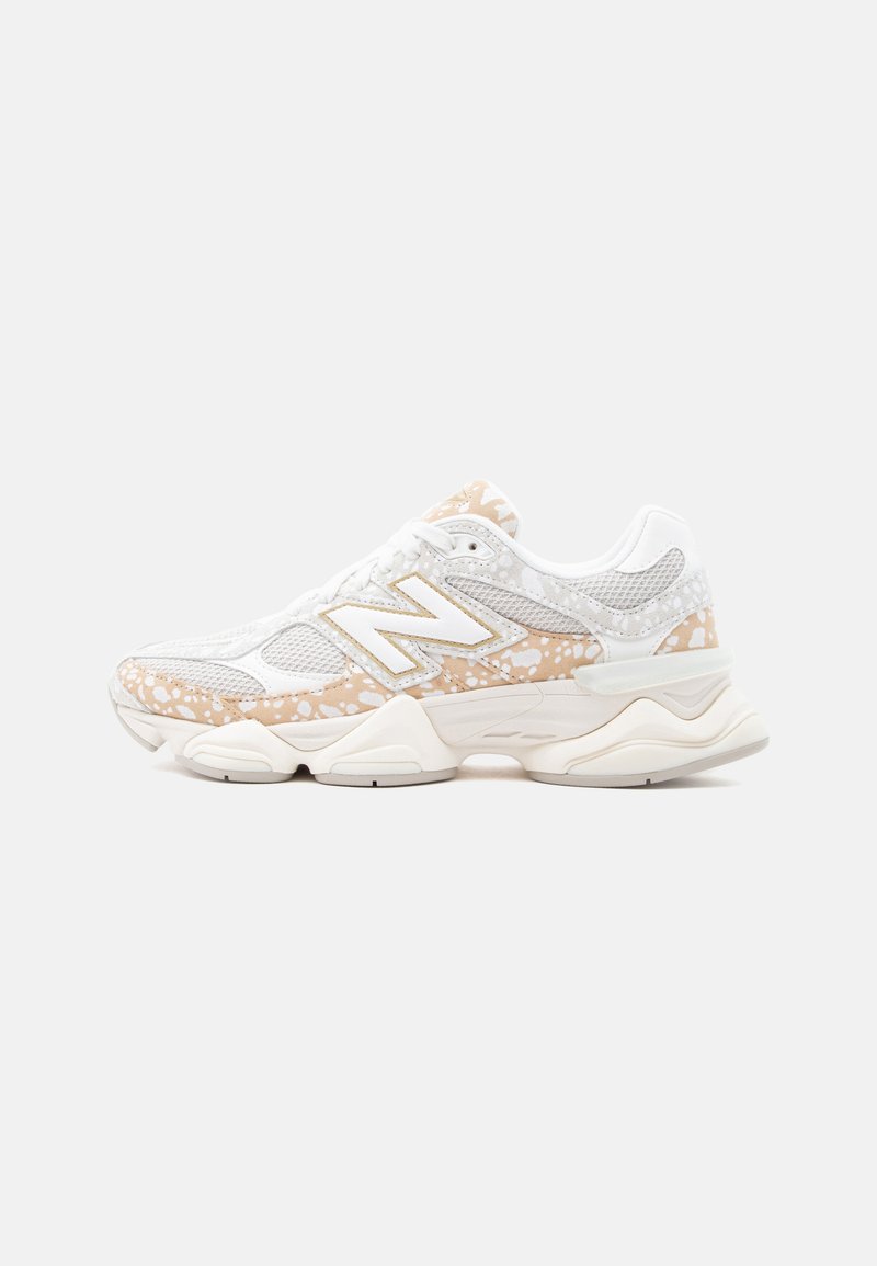 Λευκό και μπεζ αθλητικό παπούτσι New Balance με πάνελ από δίχτυ, πινελιές με σχέδιο πιτσιλιές και μαλακή σόλα, σε πλάγια όψη σε απλό φόντο.