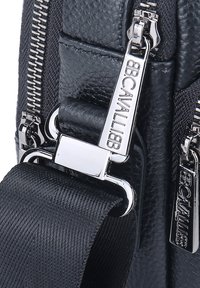 Borsa in pelle nera con texture, dotata di hardware in argento, doppie cerniere e una tracolla intrecciata con dettagli del logo per una chiusura sicura.