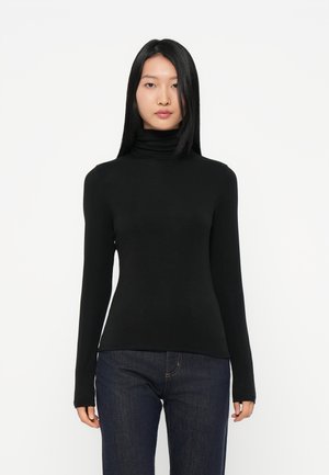 Black turtleneck top with long sleeves, made of smooth fabric. Fitted silhouette, minimalistic design, paired with dark blue jeans.