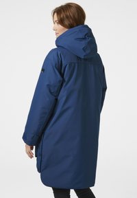 Parka impermeable azul con capucha, con un corte recto, mangas largas y botones laterales. Textura suave con un acabado mate.