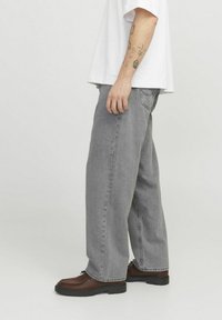 Gray wide-leg jeans with a faded finish, five-pocket design, and stitched detailing, complemented by brown lace-up shoes.