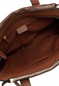 Interno di una borsa a tracolla in pelle marrone con una tasca con cerniera, foderato in tessuto e una tasca aperta all'interno.