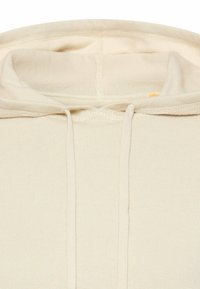 Kremowa bluza z kapturem o prążkowanej fakturze, z dużym otworem na głowę i regulowanymi sznurkami przy kapturze.