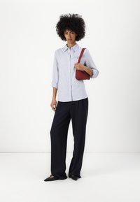 Svetlo modra prugasta srajca s kajlom, črni široki hlače in črne pointed flats. Majhna rdeča torbica je obešena čez ramo.