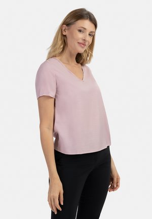 Helles rosa Kurzarmoberteil mit V-Ausschnitt, ausgestattet mit einer glatten Textur und lockerem Schnitt, kombiniert mit schwarzen Hosen.