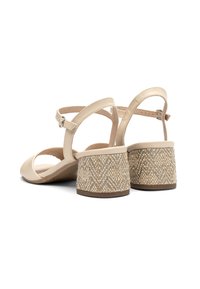 Beżowe sandały na obcasie z gładką skórzaną cholewką i plecionym bloku obcasa. Posiadają regulowany pasek wokół kostki dla pewnego dopasowania.
