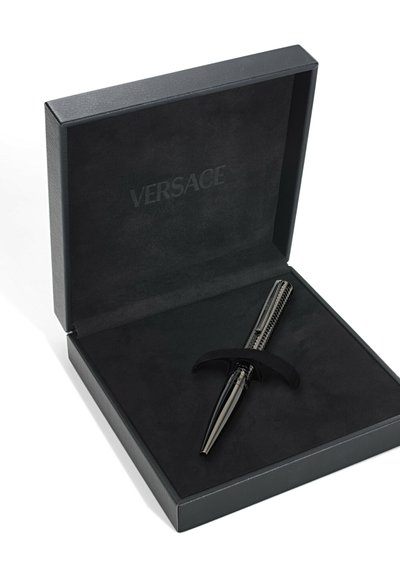 Bolígrafo negro en una caja forrada de terciopelo negro, con un diseño elegante, un cilindro texturizado y detalles brillantes, grabado con "VERSACE".