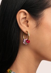 Boucles d'oreilles en or en forme de créole avec un groupe de charms floraux colorés et transparents en rose, rouge, vert et violet, présentant des textures lisses.