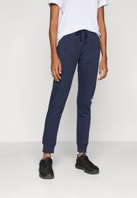 Mörkblå sweatpants i mjukt tyg, med avslappnad passform, elastisk midja med dragsko och ribbade muddar vid anklarna.