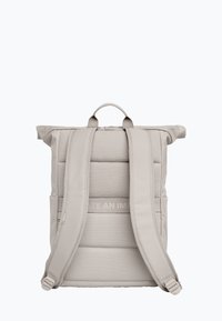 Grå rulltopp ryggsäck med vadderade remmar och kropp. Har en enkel design, slät textur och en diskret logotypdetalj på framsidan.