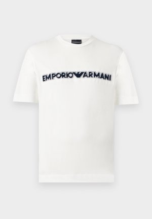 Bijela majica kratkih rukava s okruglim izrezom i crno-bijelim logotipom Emporio Armani preko prsa.