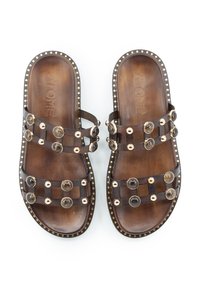 Sandali slip-on in pelle marrone con borchie decorative trasparenti, cinturini larghi e dettagli in tonalità oro. Suola piatta con poggiapiedi testurizzato.