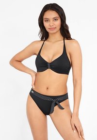 Zwarte bikini met een geknoopt ontwerp in het midden van het topje en een polkadot tailleband aan de onderkant. Soepele textuur, klassieke snit.