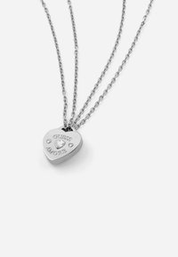 Zilveren hartvormige hanger ketting met gegraveerde "GUESS AMORE" tekst en een enkele steentjes accent op een driedubbele kettingontwerp.