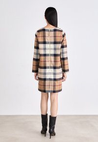 Plüüdelne villane kleit beežide, pruunide ja tumesiniste ruudutega, tagant luku ja pikkade varrukatega. Kantud mustade knee-high stiletto saapadega.