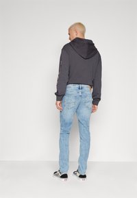 Cropped black hoodie with a hood, paired with light blue denim jeans. Sneakers feature a black and white design.