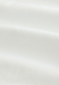 Biely textil s jemným textúrovaným mriežkovým vzorom a jemnými záhybmi vytvárajúcimi mäkké tiene.