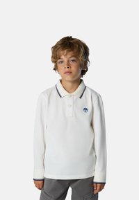 Camisa polo blanca de manga larga con una tapeta de dos botones, detalle en azul marino en el cuello y un pequeño logo redondo en el pecho. Textura suave.