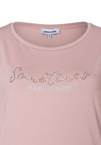 Rosa kurzärmliges T-Shirt mit Rundhalsausschnitt, auf dem "Sometimes" in Strasssteinen und darunter "MORE IS MORE" in hellblauem Text zu sehen ist.
