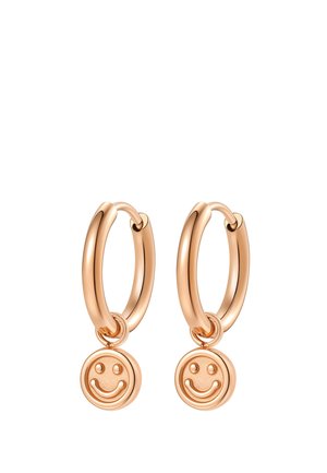 Pair of gold hoop earrings with hanging round smiley face charms on a white background.