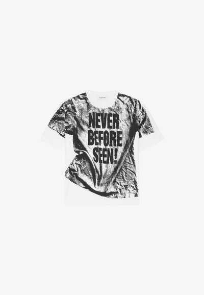 T-shirt blanc avec un imprimé graphique noir texturé et froissé, portant le texte "JAMAIS VU AVANT !" en lettres majuscules. Design à col rond.