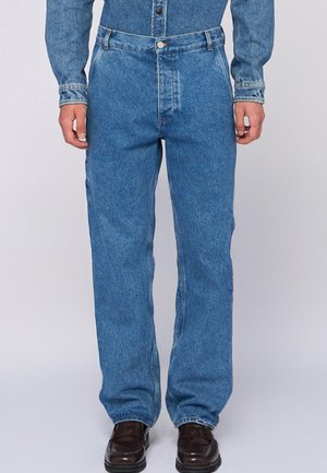 Blauwe spijkerbroek met een relaxte pasvorm, voorzien van een knoopsluiting, voorzakken en een vervaagde wassing. Gestyled met donkere leren schoenen.