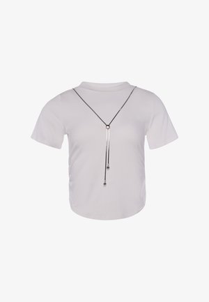 Witte top met korte mouwen en een ronde halslijn, geaccentueerd met een lange zilveren lariatketting met twee kleine ronde hangers.
