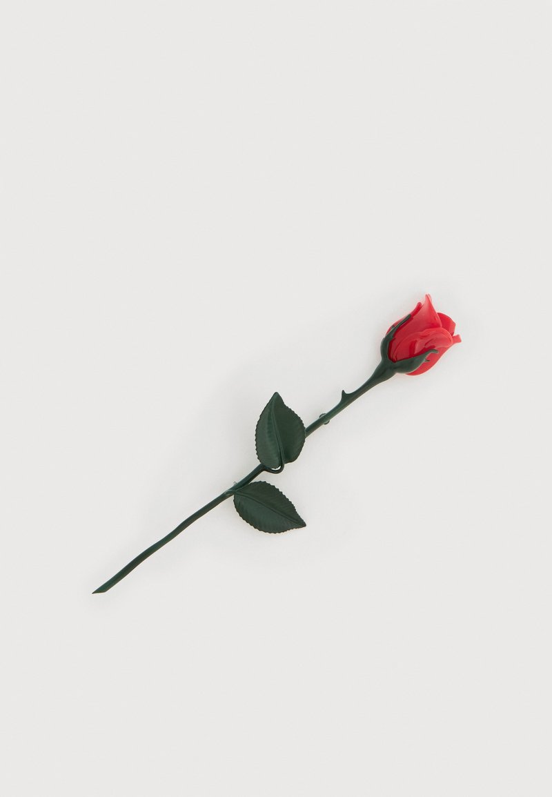 Rose rouge unique avec deux feuilles vertes sur une longue tige, sur fond blanc uni.