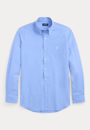 Chemise bleu clair à manches longues avec boutons, col boutonné et petit logo blanc brodé sur la poitrine gauche.