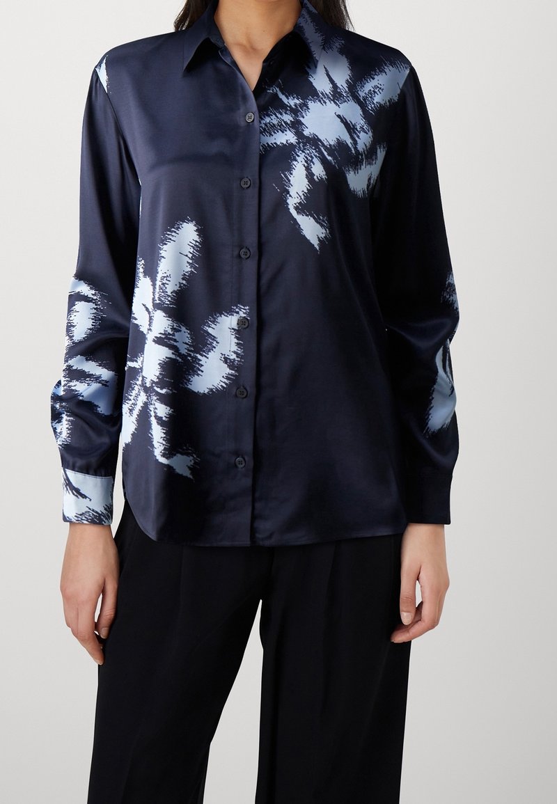Chemise en satin à manches longues de couleur marine avec un motif floral abstrait bleu clair, fermeture par boutons, col classique et poignets contrastants.
