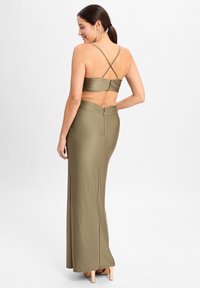 Olijfgroene tweedelige outfit met een cropped top met gekruiste bandjes en een lange rok met een zijsplit en een rits aan de achterkant.