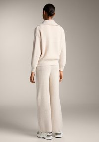 Set de loungewear de culoare crem din tricot, compus dintr-un pulover cu croi lejer și guler și pantaloni cu picioare largi, ambele cu un finisaj texturat.
