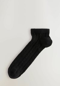 Calcetín negro de punto con borde acanalado, que presenta un patrón texturizado y talón reforzado, afinándose hacia una punta redondeada.