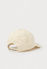 Bežs beisbola cepure, kas izgatavota no kokvilnas, ar izliekto vizieri, ventilācijas caurumiem un regulējamu siksnu ar "Calvin Klein Jeans" logotipu.