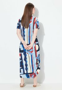 Maxi-mekko sinisen, punaisen ja kermaisen abstraktin kuvion kanssa. Lyhyet hihat, rento malli, jossa on taskut. Sileä kangas, nilkkapituisuus ja pyöristetty helma.