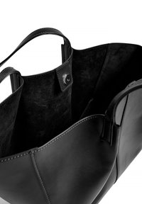 Črna usnjena torba z mehkimi notranjimi površinami, z dvema ročajema in zapiranjem na sponko. Čiste linije in minimalno šivanje za eleganten dizajn.