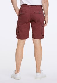 Burgundy cargoshorts med elastisk midja, sidofickor och bakfickor med knappdetaljer. Tyget verkar lätt och avslappnat.