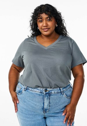 Grå v-hals t-shirt med korte ærmer, lavet af blødt stof. Sammen med lyseblå højtaljede denimjeans med knaplukning.