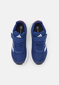 Zapatillas deportivas sintéticas azules con parte superior de malla, acentos blancos y correa de gancho y bucle. Presentan una plantilla acolchada y una suela exterior texturizada.