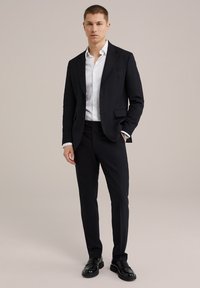 Marinblå kostym med skräddarsydd passform, vit skjorta och svarta läderskor. Rena linjer och enfärgade, inga synliga mönster eller texturer.