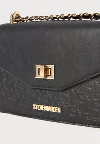Borsa nera in pelle testurizzata con motivo logo impresso, hardware dorato e tracolla a catena. Include una chiusura a scatto rettangolare.