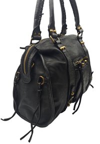 Sac à main en cuir noir avec plusieurs zips, accents en laiton, anses tressées et détails à cordon. Surface texturée avec une forme structurée.