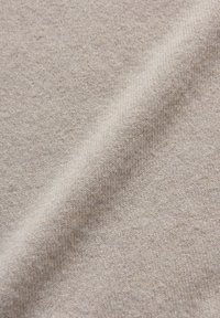 Tissu tricoté beige clair avec une texture douce, présentant un motif subtil et uniforme ainsi qu'une fluidité lisse. Idéal pour les vêtements et les accessoires.