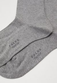 Grå bomuldsstrømper med ribbede manchetter, glat tekstur og trykt "Falke Family" logo på siden.