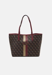 Brązowa torba na ramię z powtarzającym się tan logo, pionowymi beżowymi i burgundowymi paskami, dwoma długimi burgundowymi uchwytami oraz logo "GUESS" na środku przodu.