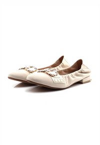 Zapatos planos beige con punta afilada, hechos de un tejido suave, que cuentan con un acento decorativo de gema metálica y lados elasticados.